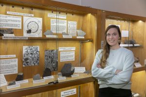 Emilie Dunham stands before a display case of meteorites.